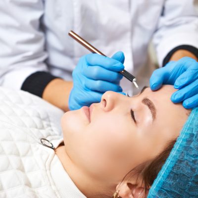 Permanent make-up master makes eyebrow correction procedure. Permanent makeup. Microblading